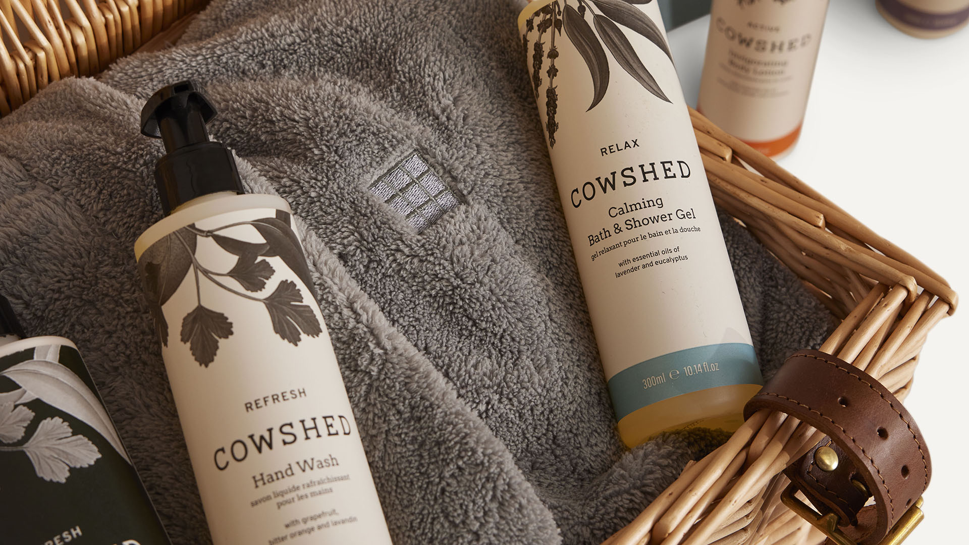 Cowshed hand wash and bath products on a grey towel