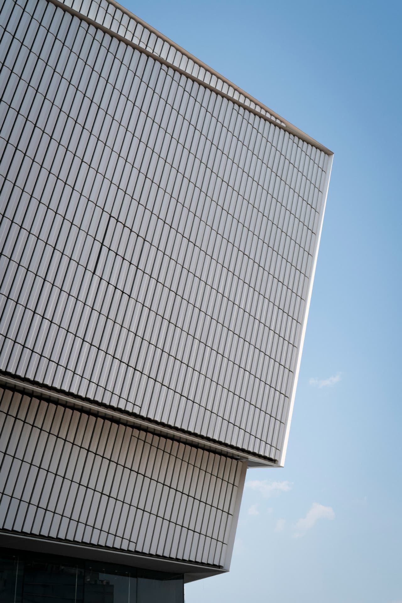 Angular ribbed facade of a modern building against a clear blue sky