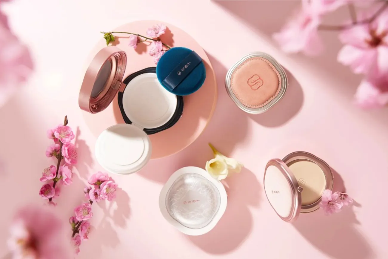 Florasis beauty compacts and powder cases arranged on a pink surface with cherry blossom branches.