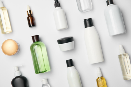Flat lay of unbranded cosmetic bottles, jars and droppers on a white background