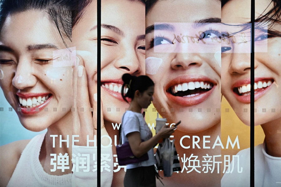 Shopper walking past a large beauty brand billboard in China