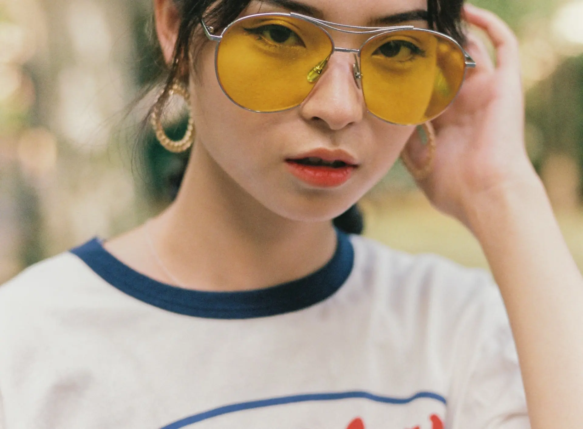 Portrait of a woman lifting yellow-tinted sunglasses