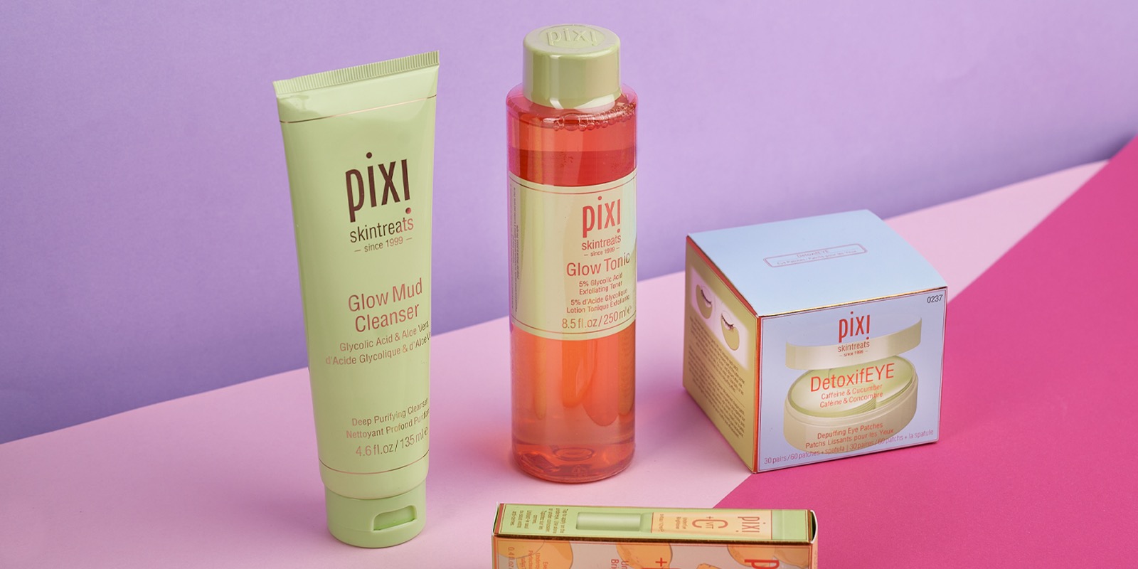 Pixi Glow Mud Cleanser and Glow Tonic on a pink and lilac backdrop