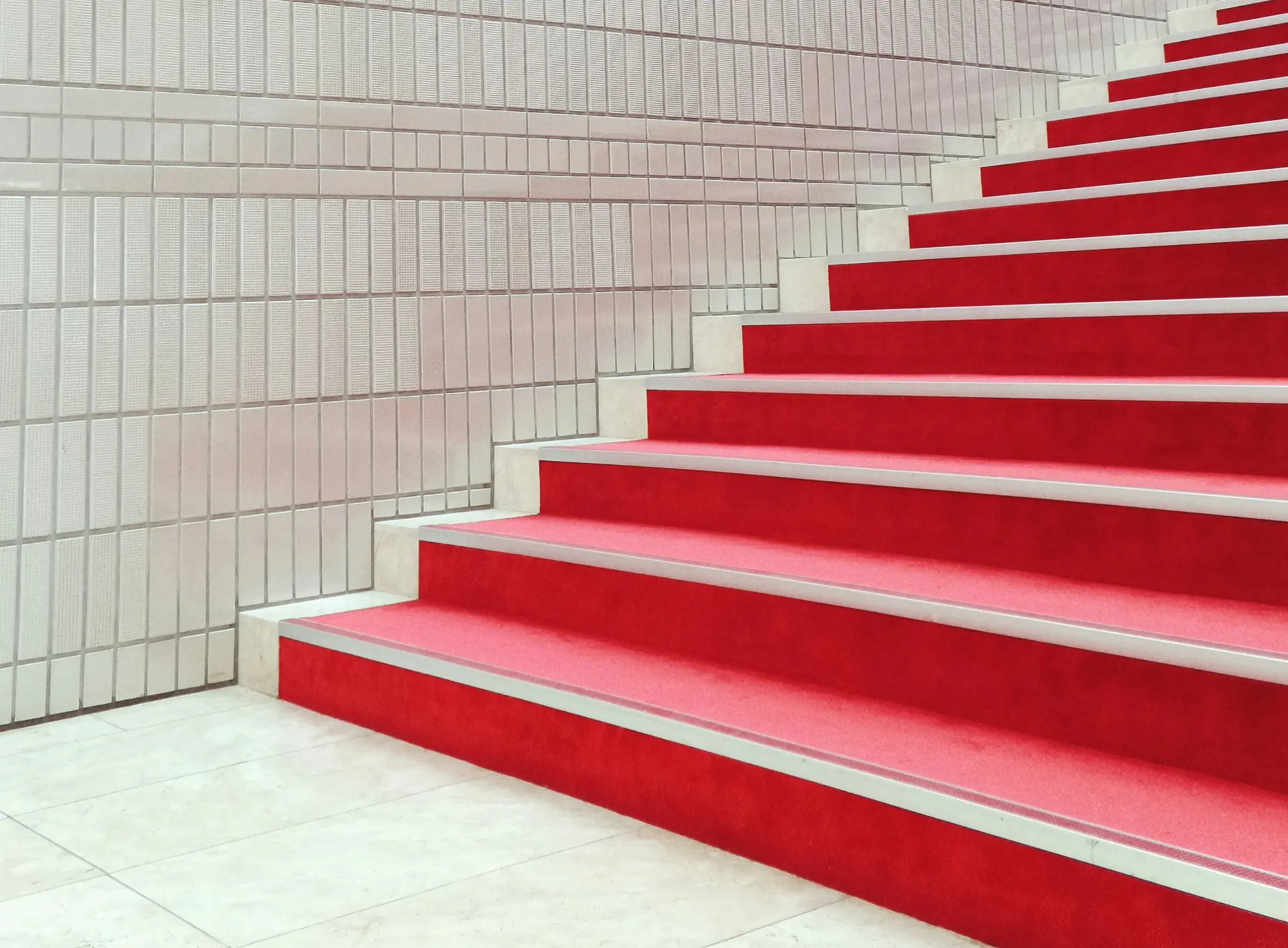 Red carpeted steps rising against a tiled wall