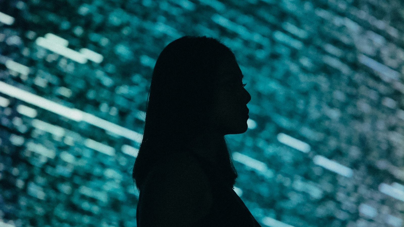 Silhouette of a woman in front of an illuminated digital display