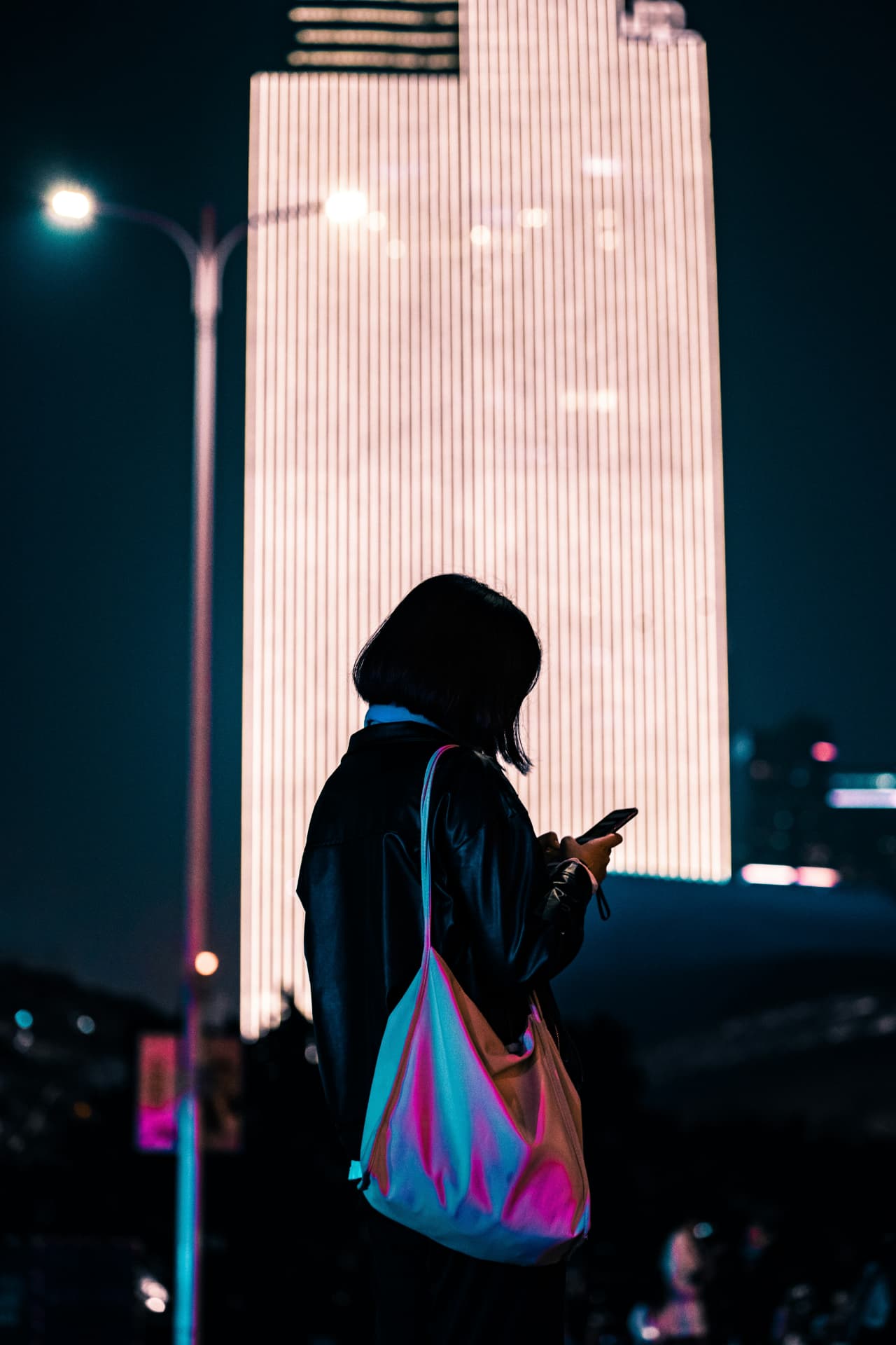 Shopper in a Chinese city at night looking at her phone